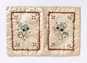  Two symmetrical embroidered floral designs on light beige fabric with a vintage look, featuring blue flowers with green leaves and small brown dots, bordered by a reddish-brown zigzag edge. Artist name and title are unknown.