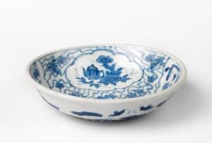  A blue and white porcelain shallow bowl with a central floral pattern and intricate blue foliage designs on the interior.