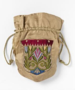  A small, light beige canvas pouch with intricate embroidery on the front, featuring a scalloped edge with magenta and white dots, white teardrop shapes with red tips, and a central floral design in blue, green, and pink with braided drawstrings.