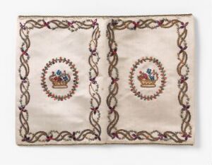  An antique-looking textile piece with an off-white background, featuring two identical circular medallions with small crowns at the center, surrounded by rings of blue, red, green, and gold, encircled by a maroon and green intertwined border. The textile reflects historical craftsmanship and regal symbolism.