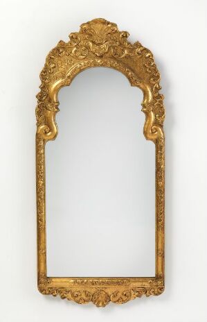  An ornate, gold-framed vertical mirror with intricate scrollwork and floral details, set against a neutral light-colored background.