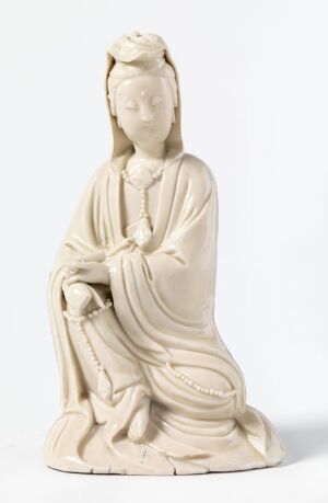  A monochromatic, creamy white sculpture of a seated, elegantly dressed figure with a serene expression, detailed drapery in the garments, and a headdress or intricate hairstyle, set against a neutral background.