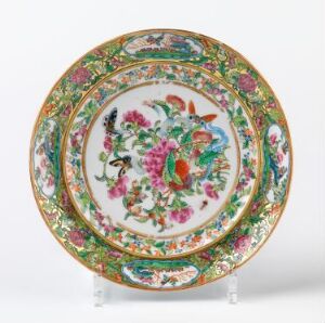 
 An intricately designed ceramic plate with a central floral motif in vivid pinks, blues, greens, and oranges, surrounded by an ornate patterned border featuring additional flowers and various decorative elements, all edged with a golden finish.