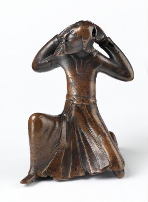  A cast bronze candlestick segment titled "Del av lysestake" by an unknown artist, featuring a flowing base resembling a draped gown that transitions into a torso-like shape with remnants of gilding and engraved decoration suggesting introspection. The object is dark brown with subtle color variations and reflects light in certain areas, suggesting