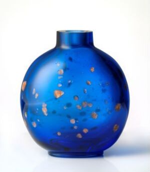  A round, cobalt blue glass vase with speckles of turquoise, amber, and rust, resembling stars against the night sky, set against a plain white background.