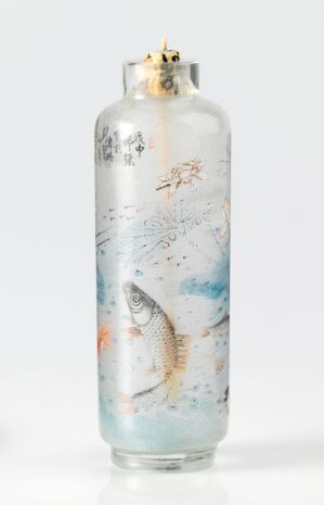  A decorative cylindrical vase adorned with pastel blue and orange watercolor designs depicting fish and plant life, with gilded detail on the rim.