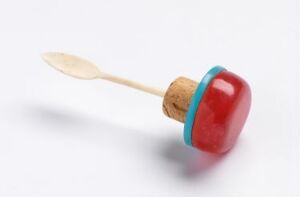  A colorful bottle stopper with a red and turquoise top attached to a wooden spoon handle against a white background.