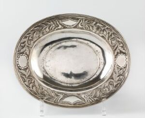  An antique oval silver plate with detailed embossed designs on the border and a plain, slightly tarnished center, displayed against a plain white background.