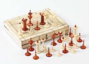  A multi-tiered, light-colored chess set with intricately carved reddish-brown pieces, set up in starting positions, on a plain white background. Artist name and title unknown.