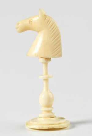  An ivory-colored knight chess piece with detailed carving, centered against a light grey background.