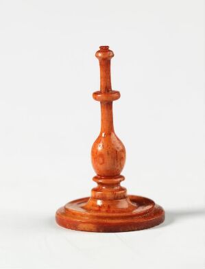  A polished wooden chess king with a reddish-brown color stands centered against a plain white to gray gradient background, highlighting the piece's detailed craftsmanship and glossy finish. Artistname and title remain unknown.