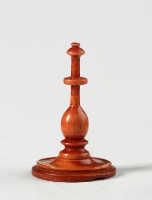  A polished wooden chess king piece with a rich mahogany color, set against a plain light gray background, demonstrating the fine craftsmanship of the piece, with detailed curves and a regal cross at the top.