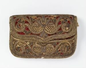  An antique, flat, rectangular embroidered pouch with gold and silver threads, red beads, and pearl-like accents on a faded gold fabric, showcasing intricate symmetrical floral patterns and a small circular clasp.