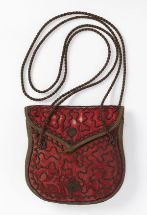  Small traditional purse with a vibrant red patterned background and a braided shoulder strap, displayed against a neutral backdrop. Artist name and title are unknown.