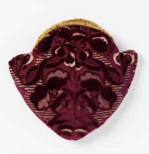  A deep maroon velvet-like fabric with a floral or vegetal pattern in a lighter shade, displaying a scalloped edge with a bright yellow band along the top against a light background. Artist and title are unknown.