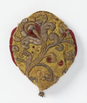  An antique golden-yellow embroidered shield-shaped pouch with intricate reddish-brown floral designs, silver-thread outlines, a red trim, and a bottom tassel, set against a white background.