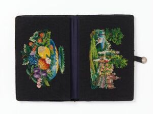  An embroidered notebook is open, showing vibrant needlework. The left page has a burst of colorful flowers and plants, featuring greens, oranges, purples, pinks, and yellows. The right page illustrates a forest scene with a wizard-like figure in green robes and a brown and orange fox in a green woodland setting, creating a magical tableau.