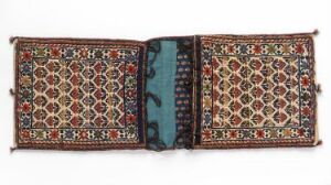 
 Intricate ethnic-style textile artwork featuring symmetrical panels with a diamond motif in red, dark blue, cream, and orange, connected by a central teal strip with a simpler geometric pattern, laid flat against a neutral background.