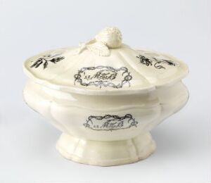  A small, cream-colored, ceramic covered dish with ribbed detailing and dark-ink illustrations, possibly floral and wildlife, on its surface.