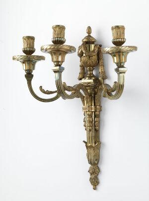  An ornate, gold-colored wall-mounted candelabra with a central figure in ceremonial armor and five arms for holding candles, featuring classical design elements and intricate patterns.