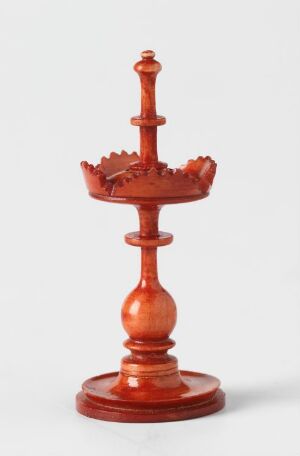  A reddish-brown candlestick holder with a round base, bulbous and tapered sections culminating in a scalloped-edge drip pan, against a plain white background.