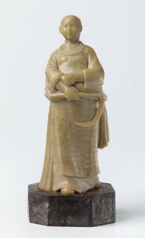  A small ivory-colored sculpture of a serene figure in flowing robes holding a smaller figure or object, standing on a dark cylindrical base.