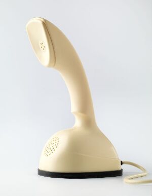  The Ericofon designed by Ralph Lysell, a sleek one-piece off-white telephone with a sculptural curvilinear shape, earpiece facing forwards, and a hidden dial pad, on a white background.