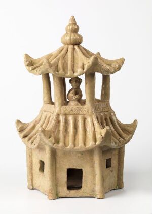  A beige ceramic figurine of an East Asian-style pagoda with multiple tiers of upturned eaves, a visible interior space through an open doorway, and a pointed finial on the top, set against a light gray background.