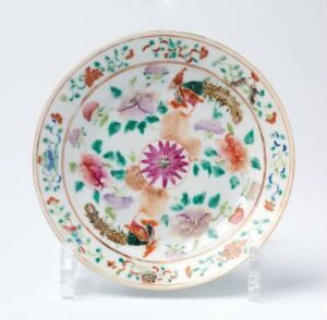  A beautifully painted ceramic plate with a vivid floral pattern featuring a large pink and purple flower in the center, surrounded by a variety of flowers and leaves in green, blue, orange, and brown, displayed on a transparent stand with a plain background. Artist name and title are unknown.