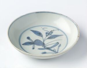  A ceramic bowl with off-white glaze featuring a painted cobalt blue botanical design inside.