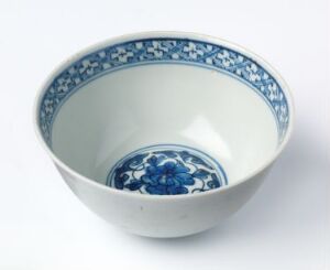  A traditional blue and white ceramic bowl with floral patterns along the rim and in the center, resting on a plain surface with a soft-focus background.