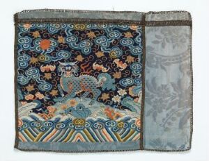  An intricate, rectangular antique textile panel with a dark blue background featuring dense, swirling cloud patterns and mythical animal figures in various shades of blue, white, orange, and green. The bottom of the main panel shows a wavy gradient pattern resembling stylized ocean waves. A separate, lighter blue section with a misty, cloud-like pattern is stitched to the right, and the textile shows signs of age with slight fraying. Artist name and title are unknown.