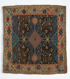  A symmetrical, square textile with a central navy blue diamond surrounded by geometric and floral patterns in dark blue, light blue, orange, and white, set against a green and rusty orange background with several decorative borders.