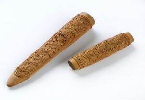  Two ornate wooden carved objects on a white background, likely a case and its lid, adorned with detailed floral or foliate patterns, displaying skilled craftsmanship.