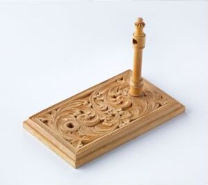  An intricately carved wooden chess king stands on a segment of a similarly carved wooden base with a swirling pattern, against a white background.