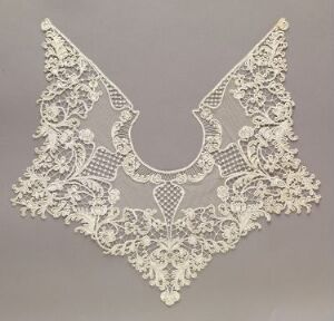  An exquisite, symmetrical white lace collar with intricate floral and geometric patterns displayed against a light grey background, embodying traditional textile craftsmanship.