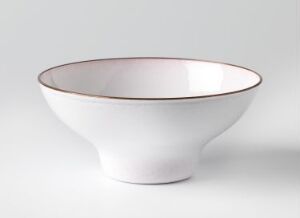  A white enameled copper bowl titled "Japan," designed by Grete Prytz Kittelsen, with a simple, elegant form and a metallic rim. The bowl tapers from a wide top to a narrow base and has a reflective white interior.