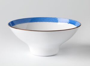  A white enamel-coated copper bowl titled "Japan" by Grete Prytz Kittelsen, tapered and with a vivid cobalt blue interior rim, exemplifying modern Scandinavian design in tableware.