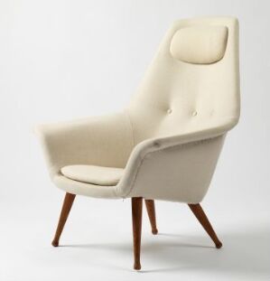  "Butterfly" chair by artist Torbjørn Afdal, with off-white wool upholstery and angled oak legs, featuring a high backrest with button details and integrated head cushion.