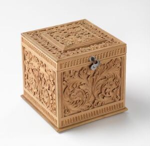  An intricately carved wooden box with detailed floral patterns on all sides and a lattice-style top with a metal clasp, set against a light grey background.