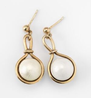  A pair of enameled and gilded silver earrings by Grete Prytz Kittelsen, with a smooth off-white central enamel inside a warm gold-toned frame, suspended from a small spherical bead and wire hooks.