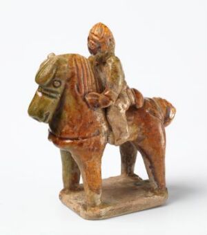  An antique sculpture of a figure riding a horse, displayed on a flat base, painted with earthy tones of burnt orange and brown, featuring detailed accents in dark tones for the tack and the rider's attire. Artistname and title are unknown.