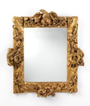  An intricately designed baroque style golden mirror frame with a bird and floral motifs at the top center, set against a pure white background. The actual mirror pane is not present within the frame.