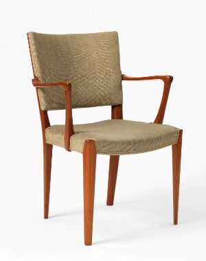  A mid-century modern chair with a warm reddish-brown wooden frame and sandy beige upholstered seat and back cushions, set against a plain light background.