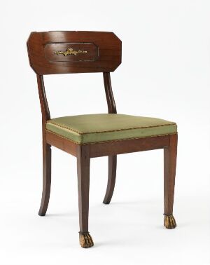  An antique wooden chair with a curved backrest featuring a floral inlay design, an olive green upholstered seat with subtle patterns, and tapered legs ending in brass-capped feet against a plain, light background.