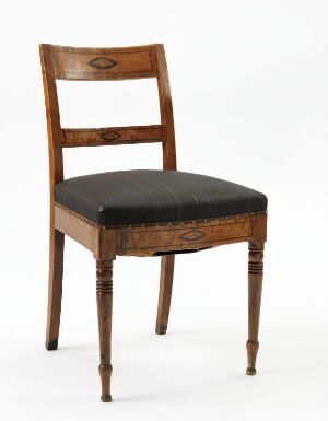  An antique chair with polished wooden frame and turned front legs, featuring a cushioned seat upholstered in dark fabric, set against an off-white background.