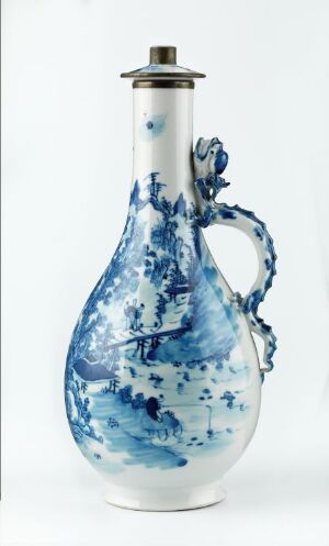  An oil lamp made of porcelain with a blue and white pattern, featuring a bulbous base, a curved handle, and a narrow neck with a metal fixture on top, set against a plain white background.