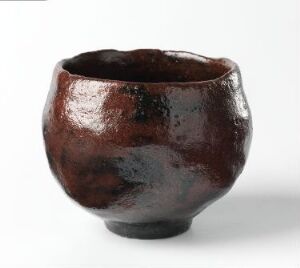  A handcrafted, glossy, deep brown ceramic bowl with an irregular shape and textural surface, displayed against a white background.