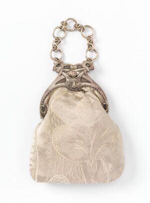  A vintage cream-colored satin purse with a floral design, featuring an ornate silver-metallic chain handle and closure, on a white background.