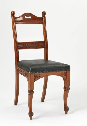  A traditional mahogany dining chair by A. Huseby & Co titled "Spisestuestol." The chair features a warm, reddish-brown color with relief carvings on the backrest and legs, and a dark leather padded seat.